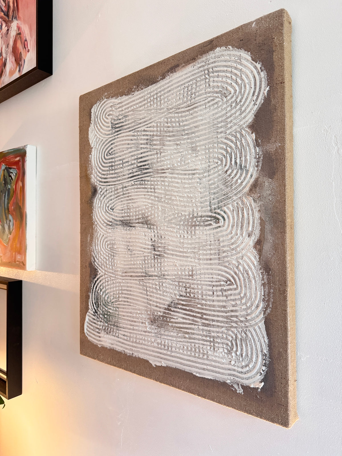 Artist Roberta Heslop with textured mixed media painting Echoes Within in studio
