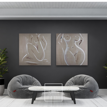 Load image into Gallery viewer, Two abstract paintings of nude figures by Roberta Heslop on a dark wall above two gray bean bag chairs with a small table.